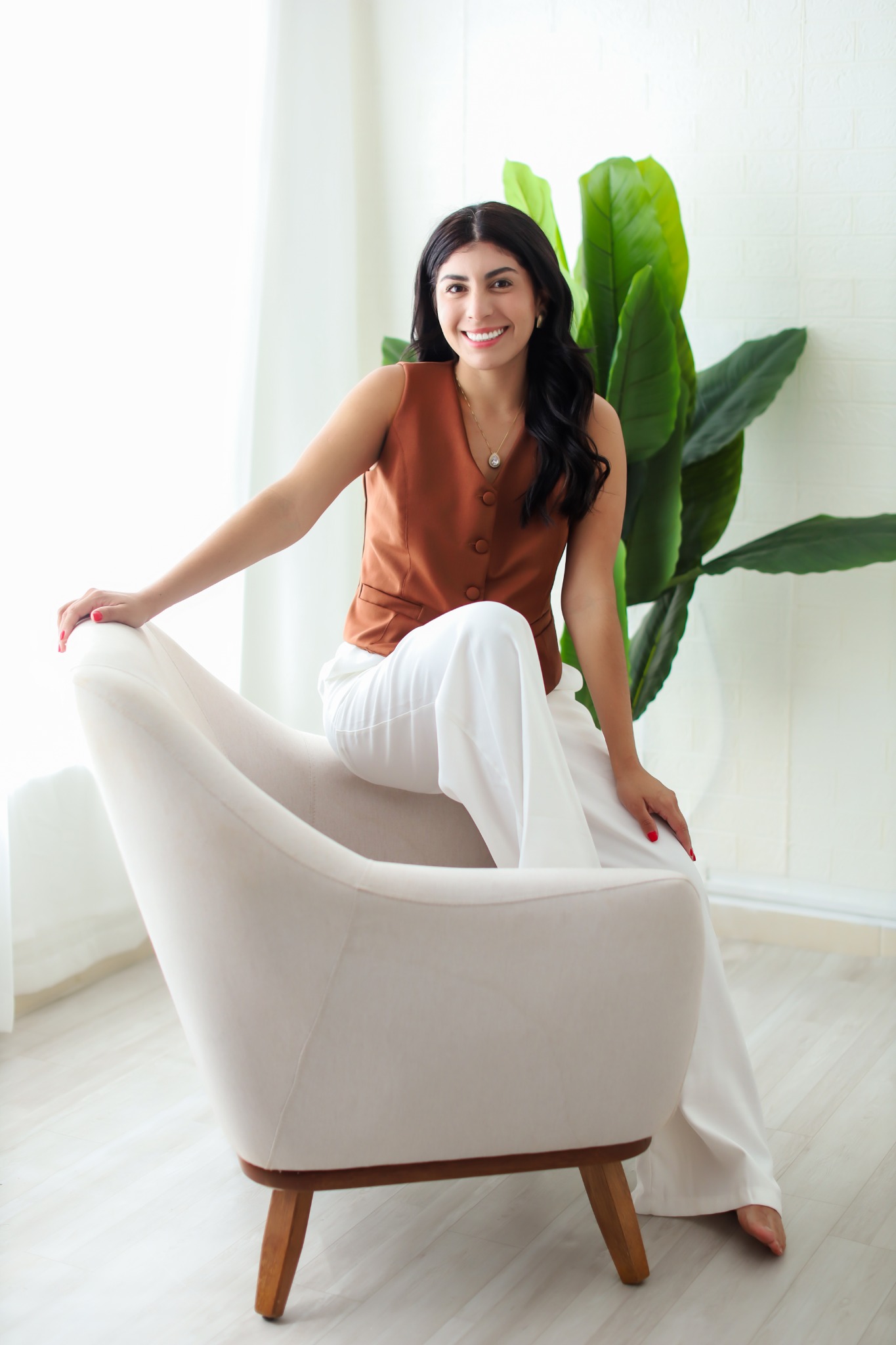Maria Aline, CEO da Lumina MKT., sentada em uma poltrona clara